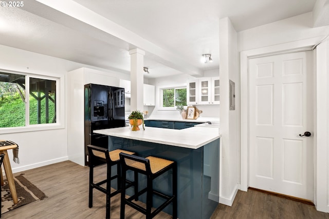 988 Savage Creek Rd, Grants Pass, OR 97527 - kitchen featuring black refrigerator with ice dispenser, white cabinets, a breakfast bar area, baseboards, and light countertops
