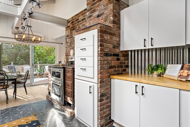 988 Savage Creek Rd, Grants Pass, OR 97527 - kitchen featuring range with two ovens, white cabinetry, wood finished floors, brick wall, and a chandelier