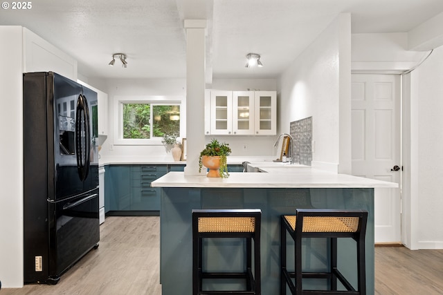 988 Savage Creek Rd, Grants Pass, OR 97527 - kitchen with freestanding refrigerator, a kitchen breakfast bar, glass insert cabinets, light countertops, and white cabinetry