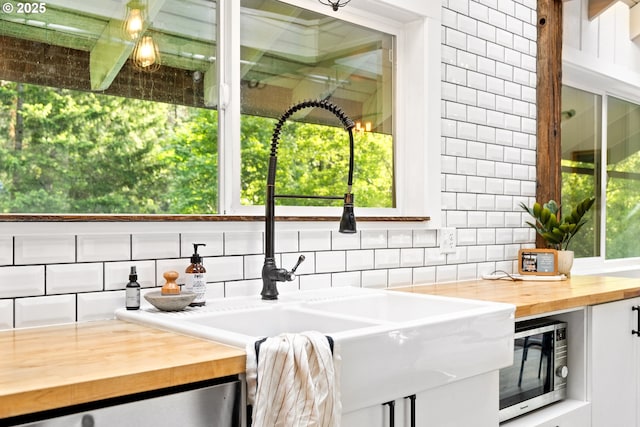 988 Savage Creek Rd, Grants Pass, OR 97527 - kitchen featuring butcher block counters, stainless steel microwave, a sink, and tasteful backsplash