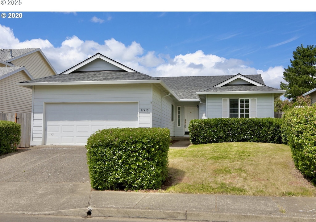 ranch-style house with a garage, concrete driveway, roof with shingles, and a front lawn