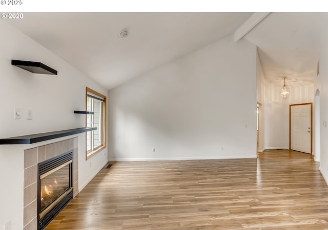 unfurnished living room featuring light wood finished floors, a fireplace, baseboards, and beamed ceiling