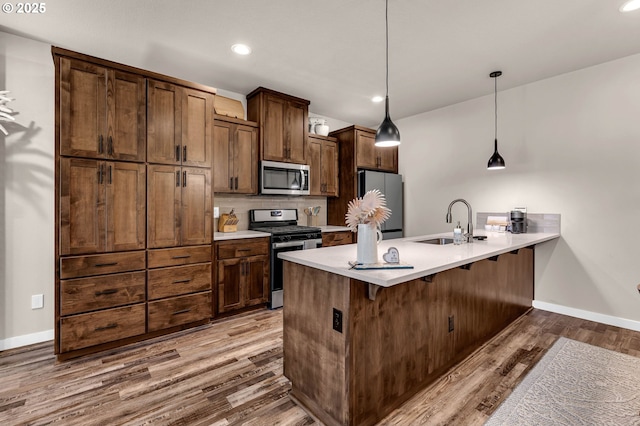 13009 NE 106th Cir, Vancouver, WA 98682 - kitchen featuring stainless steel appliances, a sink, a peninsula, wood finished floors, and a kitchen bar