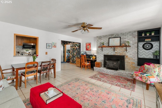 living room with light tile patterned floors, ceiling fan, and a wood stove