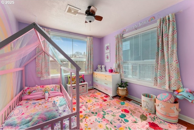 bedroom featuring visible vents, baseboards, a textured ceiling, and a ceiling fan