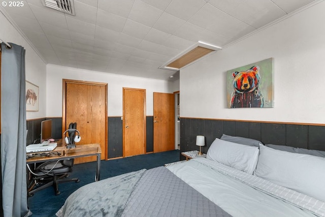 carpeted bedroom featuring crown molding, visible vents, and a wainscoted wall