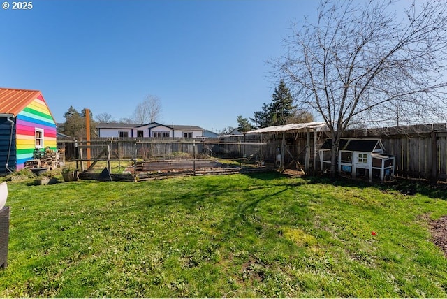 view of yard featuring an outbuilding, a vegetable garden, a fenced backyard, and exterior structure