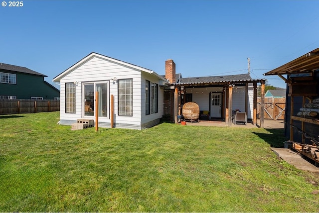 back of house with a patio, a fenced backyard, a lawn, and a chimney