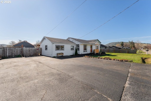 ranch-style home with a front lawn and fence