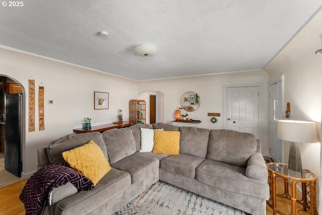 living area featuring arched walkways, a textured ceiling, and light wood-type flooring