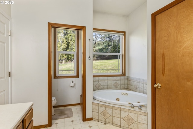 bathroom with vanity, tile patterned flooring, a relaxing tiled tub, and toilet