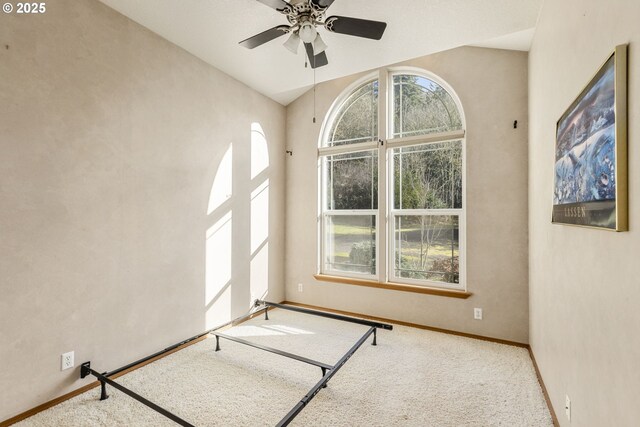 carpeted empty room featuring ceiling fan and vaulted ceiling