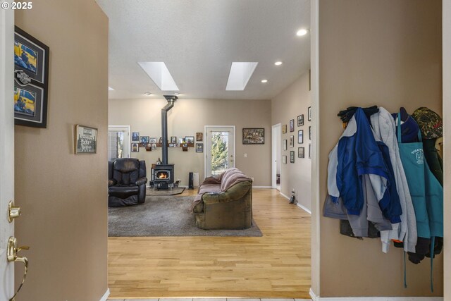 living room with hardwood / wood-style flooring, a wood stove, and a skylight