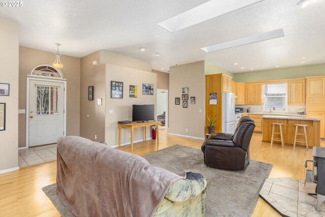 living room with light wood-type flooring and a skylight