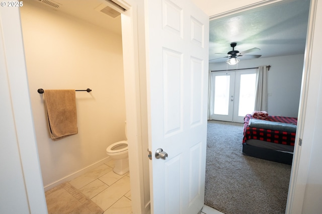 bathroom featuring a ceiling fan, visible vents, toilet, french doors, and baseboards