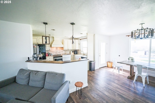 kitchen with custom exhaust hood, tasteful backsplash, open floor plan, a chandelier, and dark wood-style floors