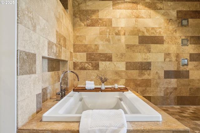 bathroom with a sink and tiled tub