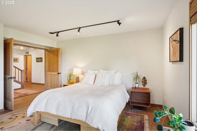 bedroom featuring visible vents, track lighting, and wood finished floors