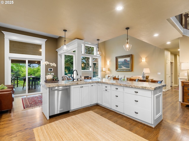 kitchen with a sink, open floor plan, dishwasher, pendant lighting, and white cabinetry
