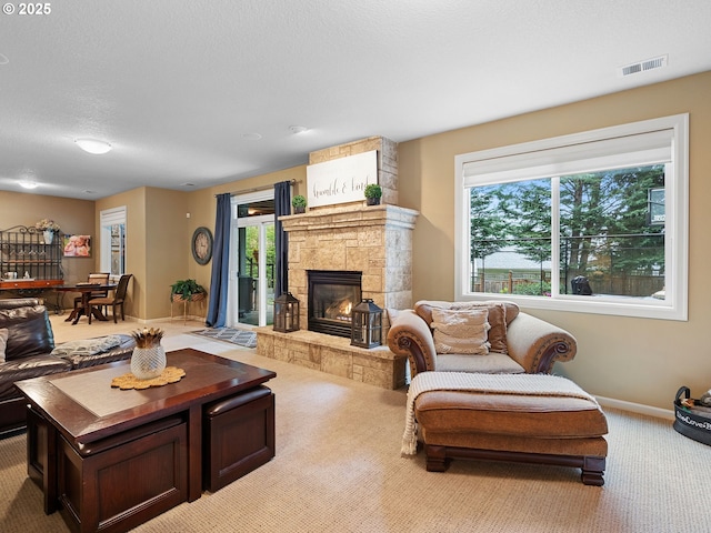 living area with a fireplace, carpet flooring, visible vents, and plenty of natural light