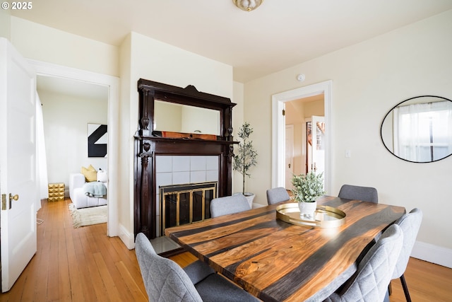 dining room featuring light hardwood / wood-style floors and a tile fireplace