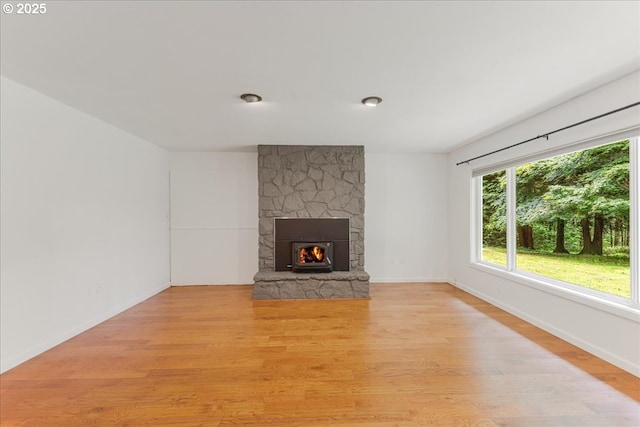 5713 Lewis River Rd, Ariel, WA 98603 - unfurnished living room featuring a stone fireplace, light wood-style flooring, healthy amount of natural light, and baseboards