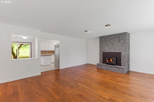 5713 Lewis River Rd, Ariel, WA 98603 - unfurnished living room featuring light wood-style floors, a stone fireplace, and baseboards