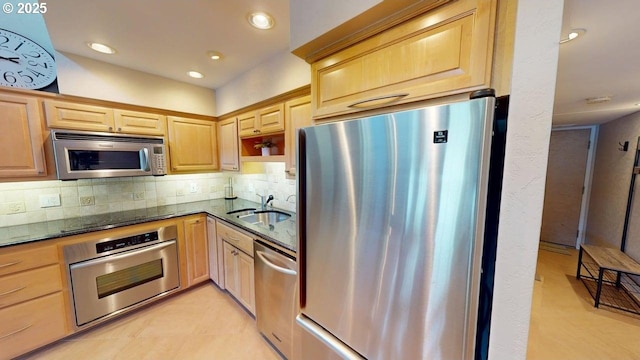 kitchen with a sink, stainless steel appliances, light brown cabinets, and backsplash