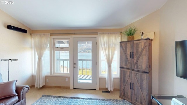doorway with light tile patterned floors, visible vents, and baseboards
