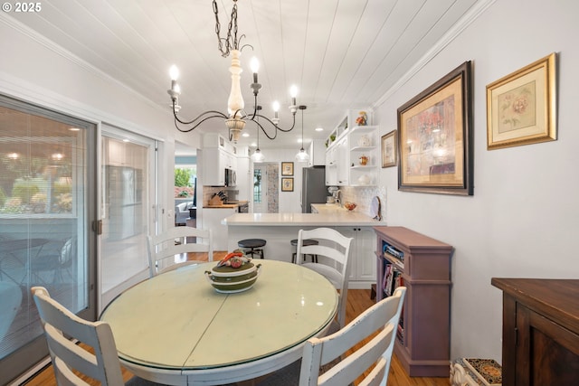 dining room featuring ornamental molding, an inviting chandelier, light wood-type flooring, and wooden ceiling