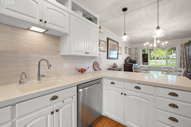 kitchen featuring a peninsula, a sink, white cabinets, stainless steel dishwasher, and decorative backsplash