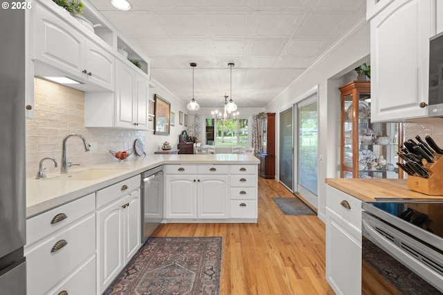 kitchen featuring a peninsula, light wood-style flooring, a sink, white cabinetry, and appliances with stainless steel finishes
