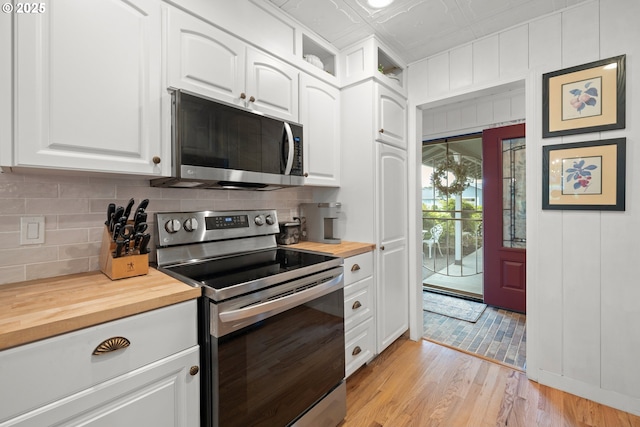 kitchen with stainless steel appliances, an ornate ceiling, light wood-style flooring, white cabinetry, and wooden counters