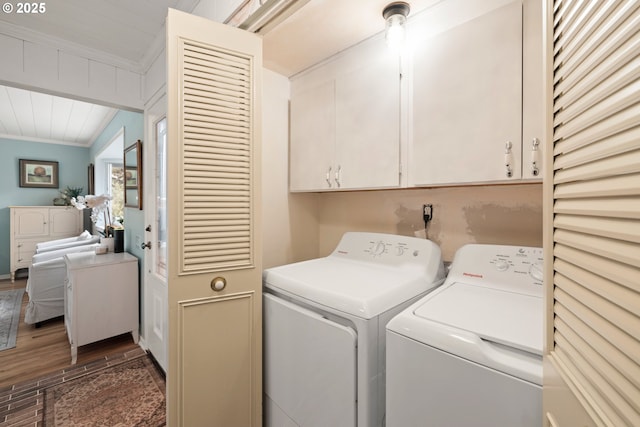 laundry area featuring washing machine and clothes dryer, dark wood-style flooring, ornamental molding, and cabinet space