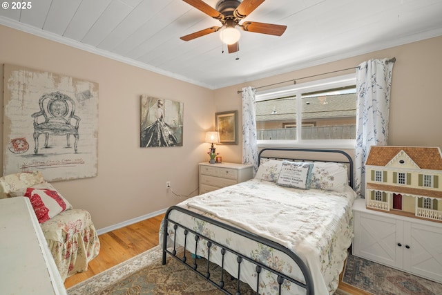 bedroom with baseboards, ceiling fan, crown molding, and wood finished floors