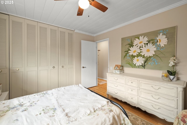 bedroom featuring ceiling fan, ornamental molding, a closet, and light wood-style floors