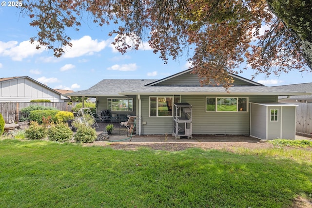 rear view of house with a yard, roof with shingles, fence, and a patio area
