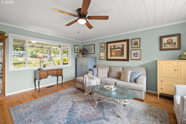 living room featuring wood finished floors, visible vents, crown molding, a ceiling fan, and baseboards