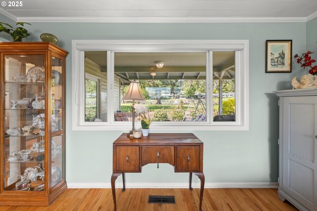 interior space featuring visible vents, wood finished floors, baseboards, and ornamental molding
