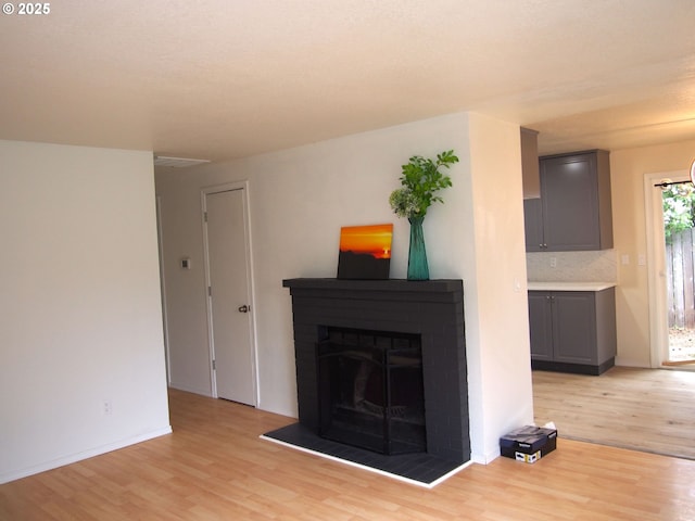 unfurnished living room featuring light wood-style floors, baseboards, and a fireplace with raised hearth