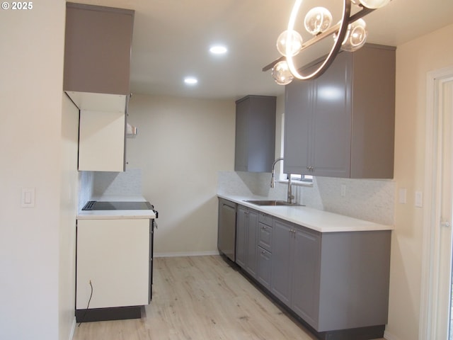 kitchen with a sink, gray cabinets, tasteful backsplash, and a notable chandelier