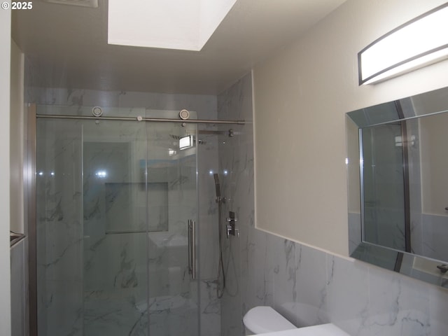 bathroom with a marble finish shower and toilet