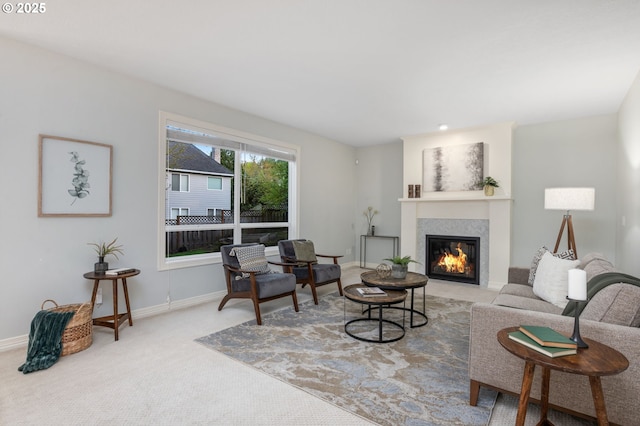 carpeted living room featuring a glass covered fireplace and baseboards
