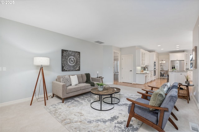 living area featuring baseboards and light carpet