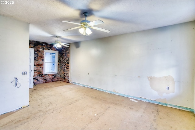 empty room with ceiling fan, brick wall, and a textured ceiling