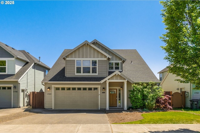 craftsman-style house featuring fence, driveway, a garage, board and batten siding, and a shingled roof