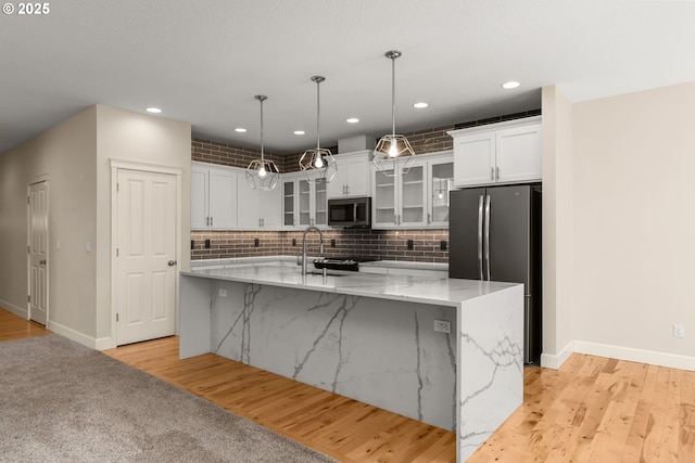 kitchen featuring freestanding refrigerator, baseboards, white cabinetry, and a large island