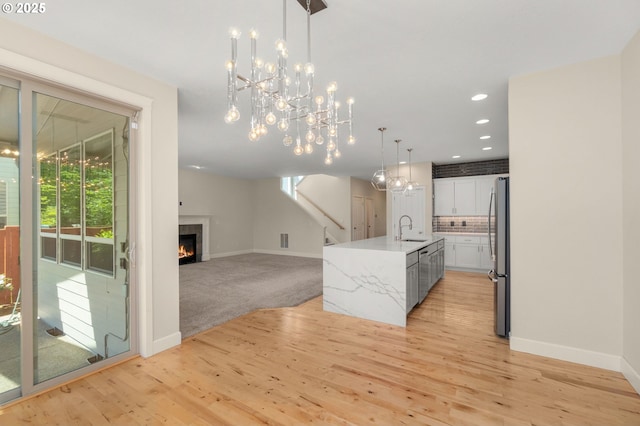 kitchen with freestanding refrigerator, a notable chandelier, baseboards, and a sink