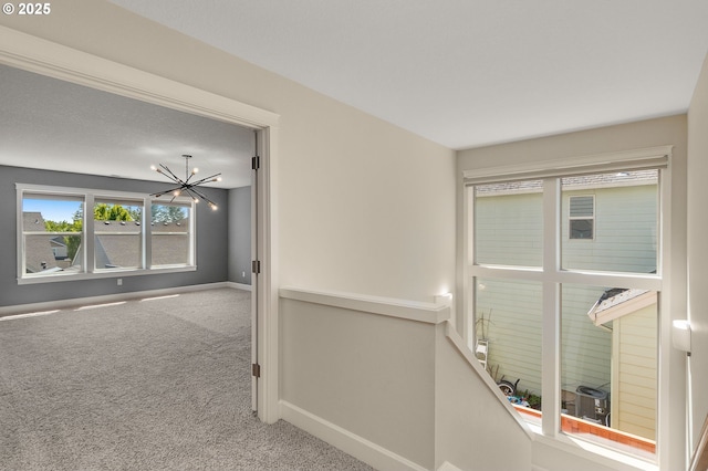 interior space with baseboards, a notable chandelier, and carpet flooring