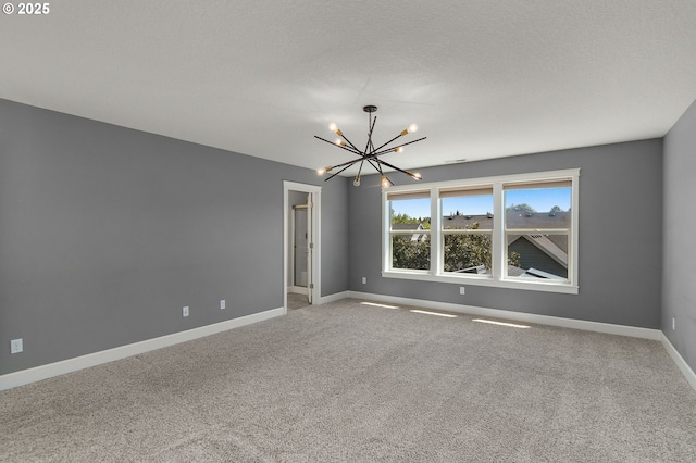 spare room featuring baseboards, a chandelier, and carpet floors
